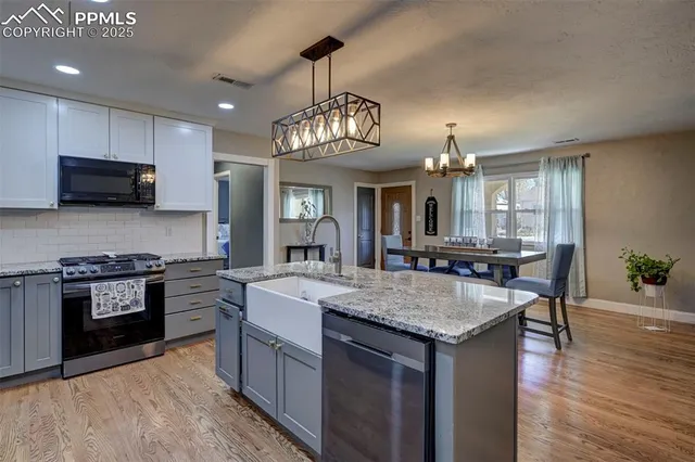 a large kitchen with granite countertop a stove top oven a sink dishwasher a dining table and chairs with wooden floor