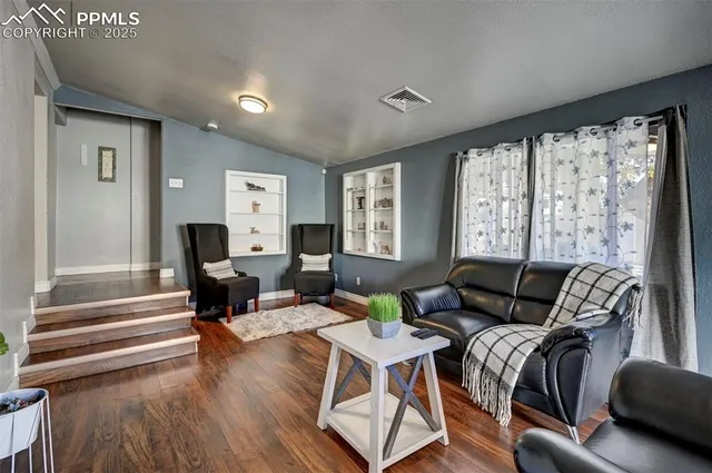 a living room with furniture floor to ceiling window and wooden floor