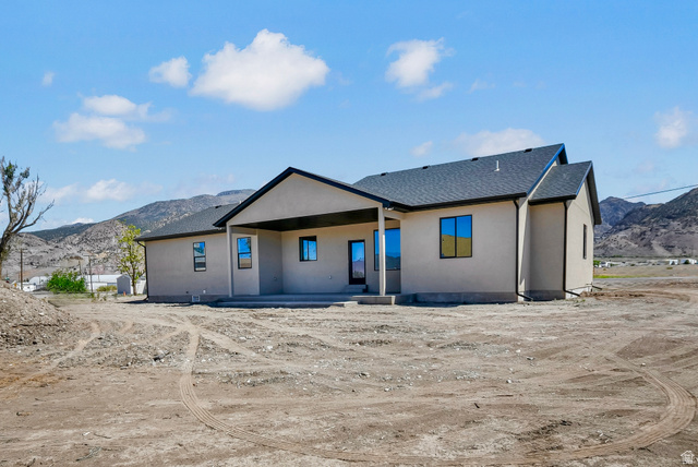 840 South Jones Road Monroe, UT 84754 - Photo 35 of 52 Stucco exterior with a covered patio, dark asphalt shingle roof, and black window frames