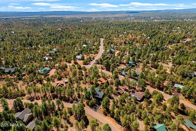 an aerial view of residential house with parking and trees