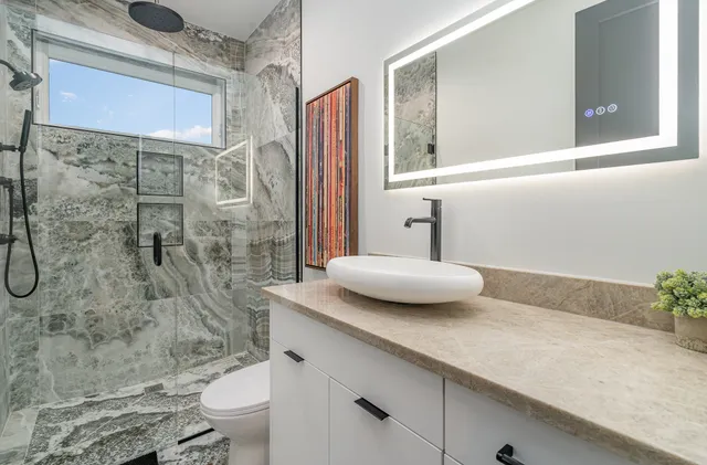 a bathroom with a granite countertop sink a toilet and shower