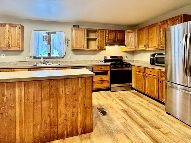 a kitchen with stainless steel appliances granite countertop a sink a stove cabinets and wooden floor