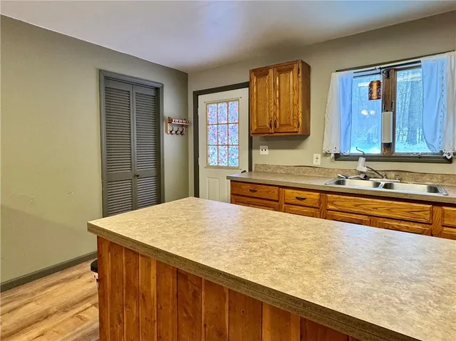 a kitchen with stainless steel appliances kitchen island granite countertop a refrigerator a sink dishwasher and wooden cabinets with wooden floor