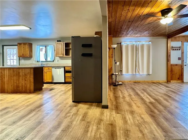 a large kitchen with stainless steel appliances a large counter top a stove a refrigerator white cabinets and wooden floor