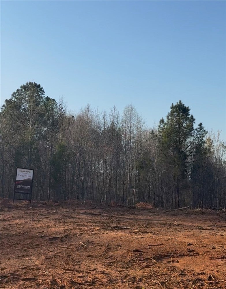 This expansive lot, cleared and ready for development, offers a serene setting bordered by mature trees.