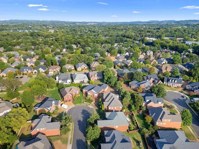 an aerial view of residential houses with outdoor space and trees