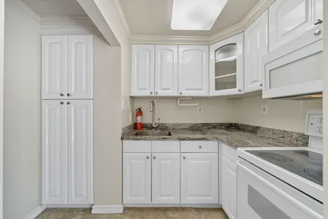 a kitchen with granite countertop white cabinets and sink