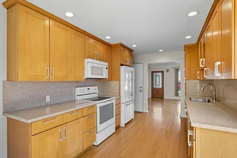 a kitchen with stainless steel appliances a stove a sink cabinets and a wooden floor