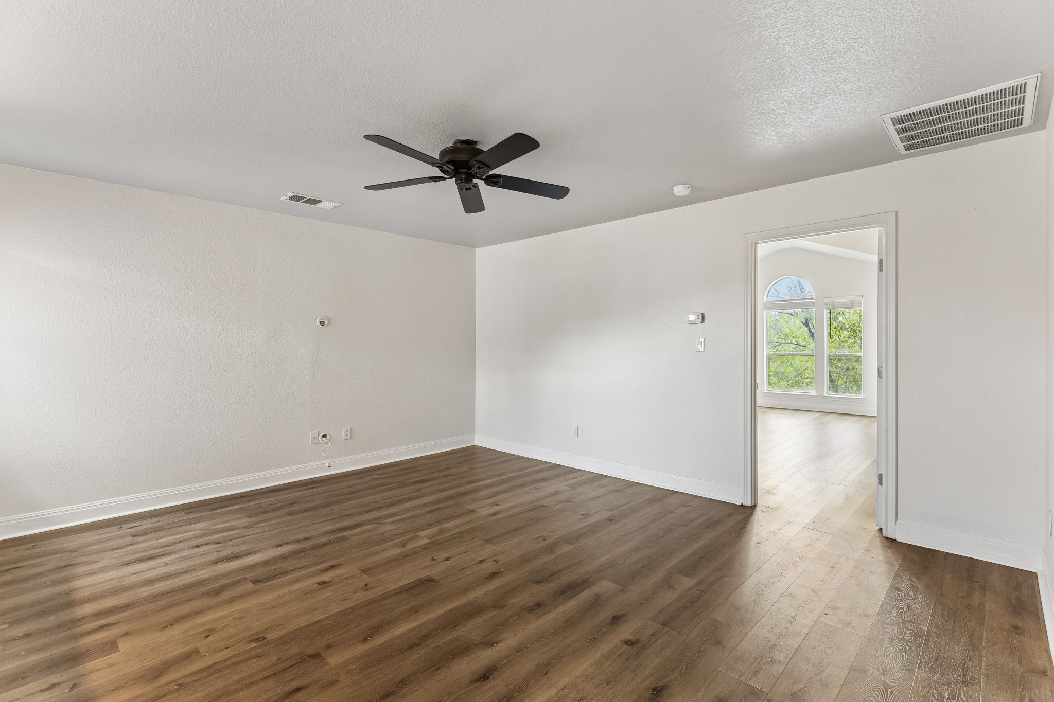 114 Aria Ridge, Unit 802 Lakeway, TX 78738 - Photo 22 of 37 Hardwood-style flooring extends into an adjacent room with a vaulted ceiling and an arched window.