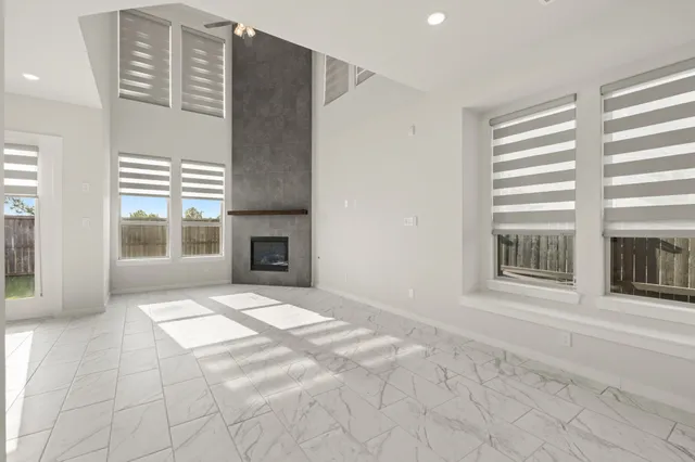 a view of an empty room with a window and a kitchen