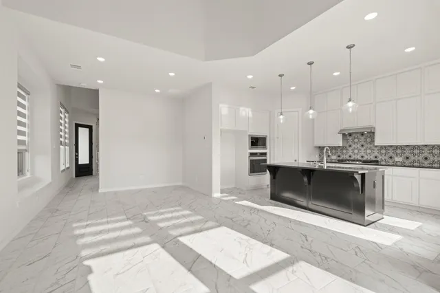 a large white kitchen with a refrigerator and a stove top oven