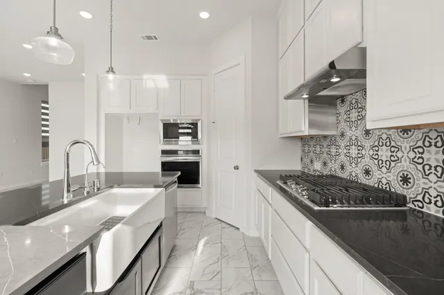 a kitchen with granite countertop a sink stove and cabinets
