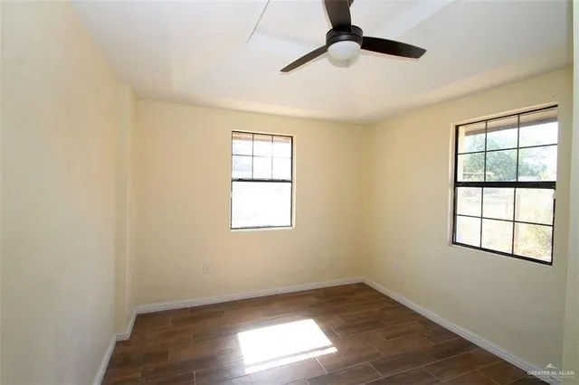 an empty room with wooden floor cabinet and windows