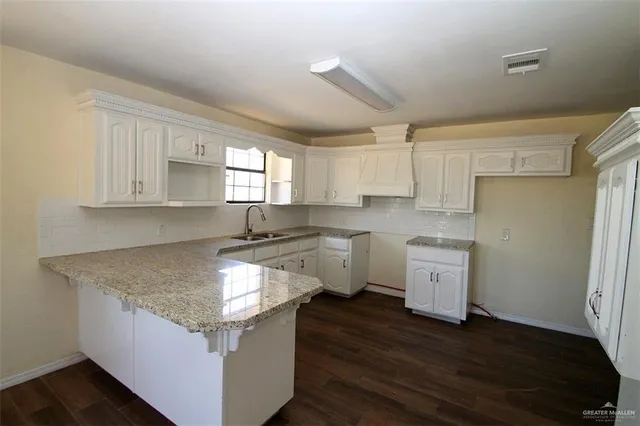 a kitchen with granite countertop a sink cabinets and wooden floor