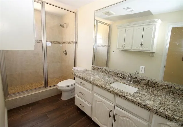 a bathroom with a granite countertop sink toilet and shower