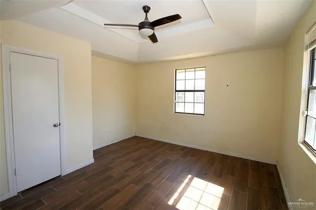 a view of empty room with wooden floor and fan