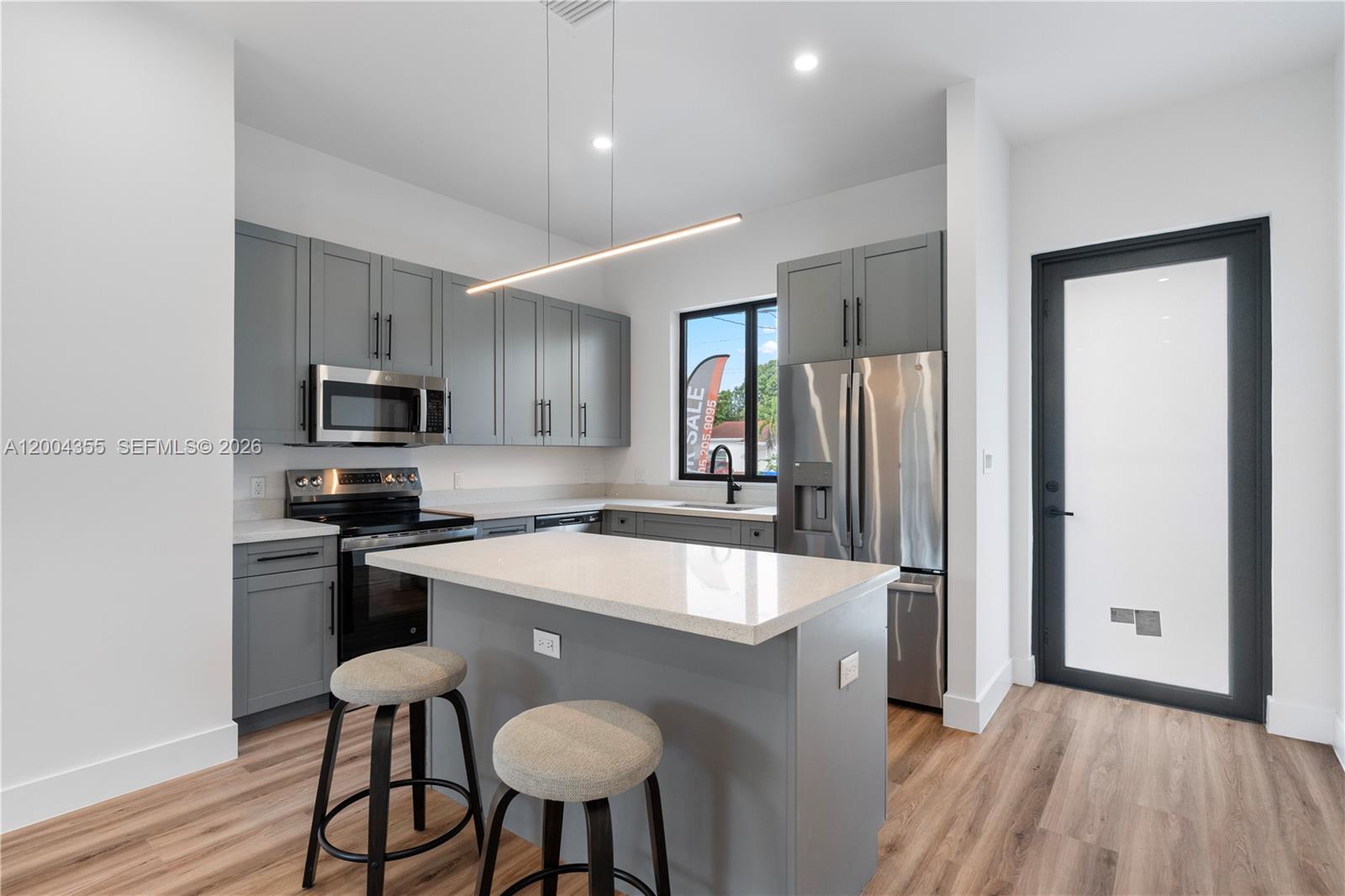 4518 Northwest 4th Street Miami, FL 33126 - Photo 2 of 23 a kitchen with stainless steel appliances granite countertop a sink a stove a refrigerator and island with wooden floor