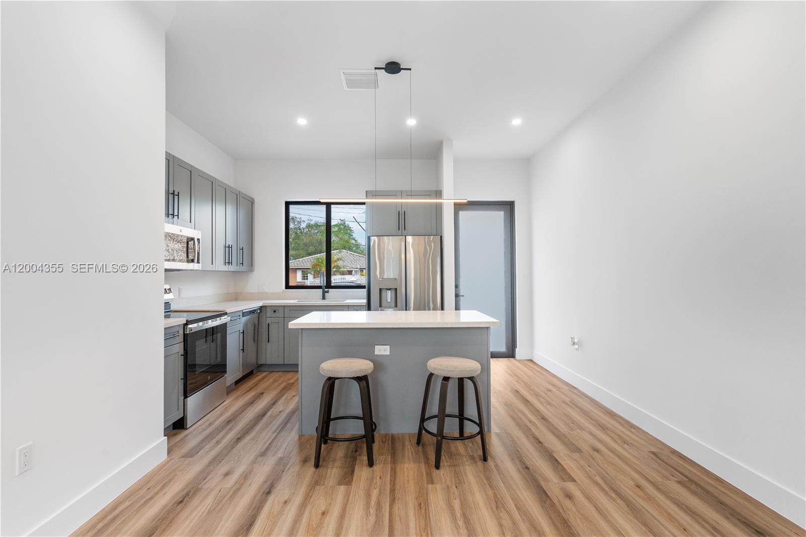 4518 Northwest 4th Street Miami, FL 33126 - Photo 7 of 23 a kitchen with stainless steel appliances granite countertop a stove top oven a sink dishwasher a dining table and chairs with wooden floor