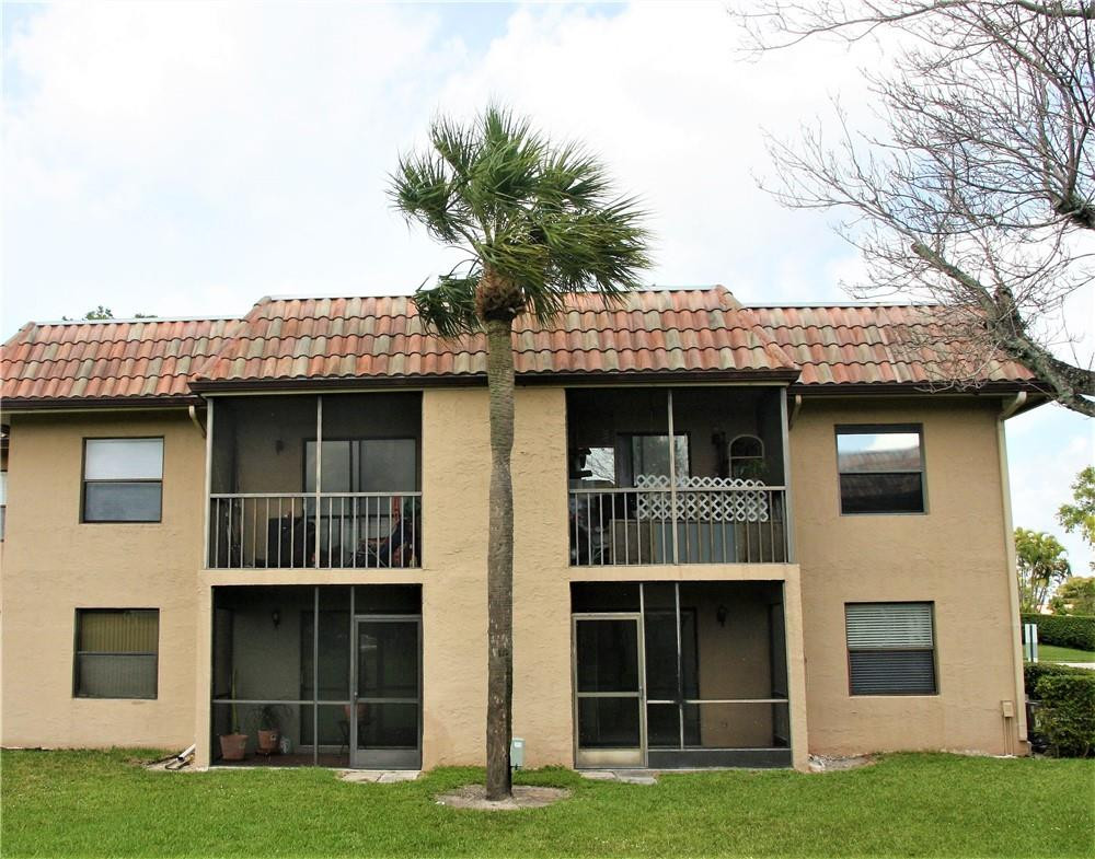 6796 Palmetto Circle South, Unit 101 Boca Raton, FL 33433 - Photo 27 of 29 a front view of a house with a garden and plants