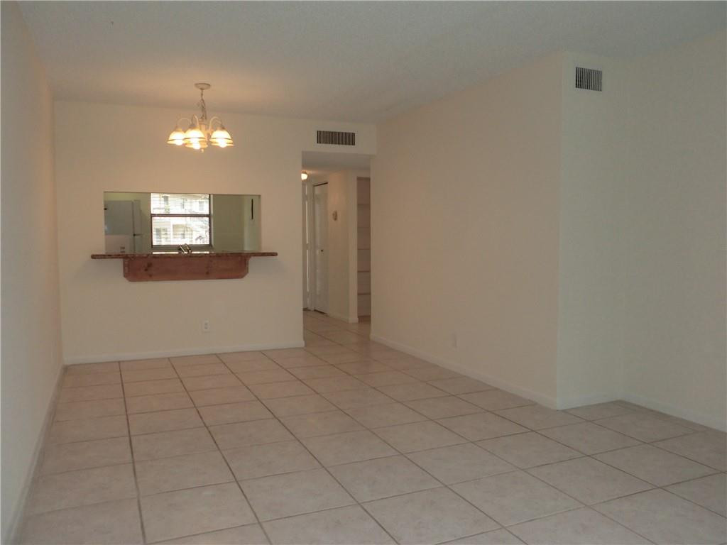 6796 Palmetto Circle South, Unit 101 Boca Raton, FL 33433 - Photo 6 of 29 an empty room with chandelier fan and windows