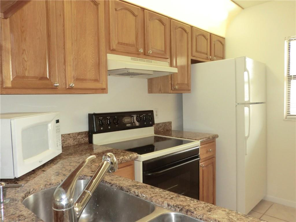 6796 Palmetto Circle South, Unit 101 Boca Raton, FL 33433 - Photo 8 of 29 a kitchen with stainless steel appliances granite countertop a refrigerator stove and white cabinets