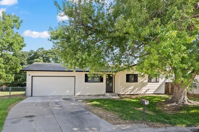 a front view of a house with a garden and trees