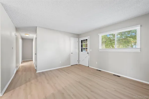 a view of an empty room with wooden floor and a window