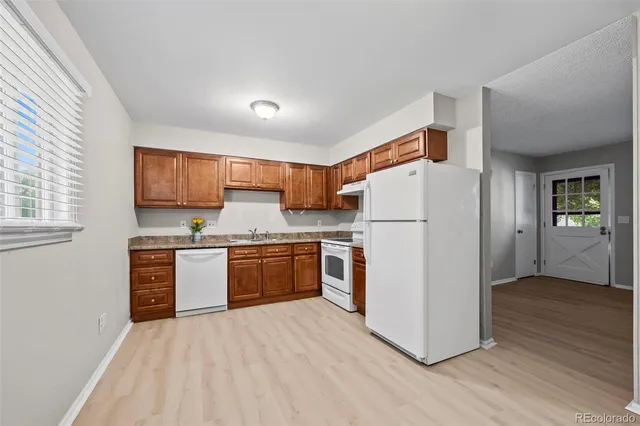 a kitchen with stainless steel appliances granite countertop a refrigerator sink and wooden cabinets
