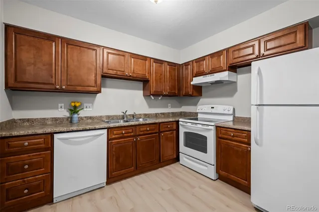 a kitchen with stainless steel appliances granite countertop a stove top oven a sink and dishwasher a refrigerator with wooden cabinets