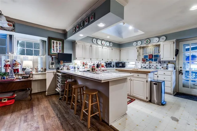 a kitchen with stainless steel appliances kitchen island granite countertop a sink dishwasher and white cabinets with wooden floor