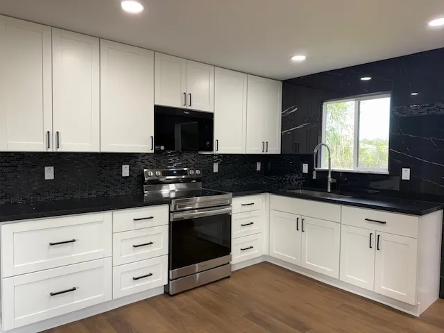 a kitchen with granite countertop white cabinets and black appliances