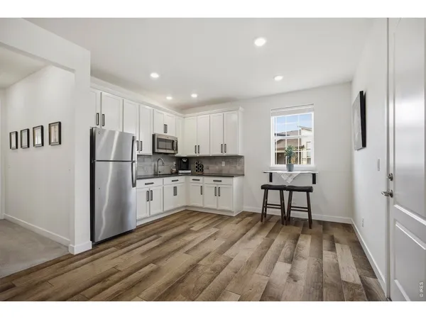 a kitchen with stainless steel appliances refrigerator wooden floor dining table and chairs