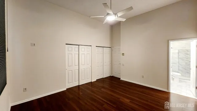 an empty room with wooden floor chandelier fan and windows