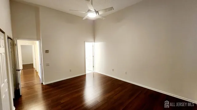 an empty room with wooden floor and ceiling fan