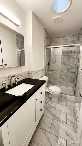 a bathroom with a granite countertop sink toilet and shower