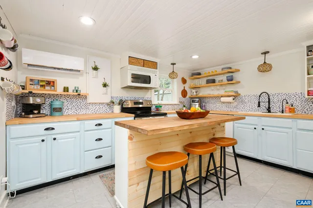 a kitchen with white cabinets and chairs