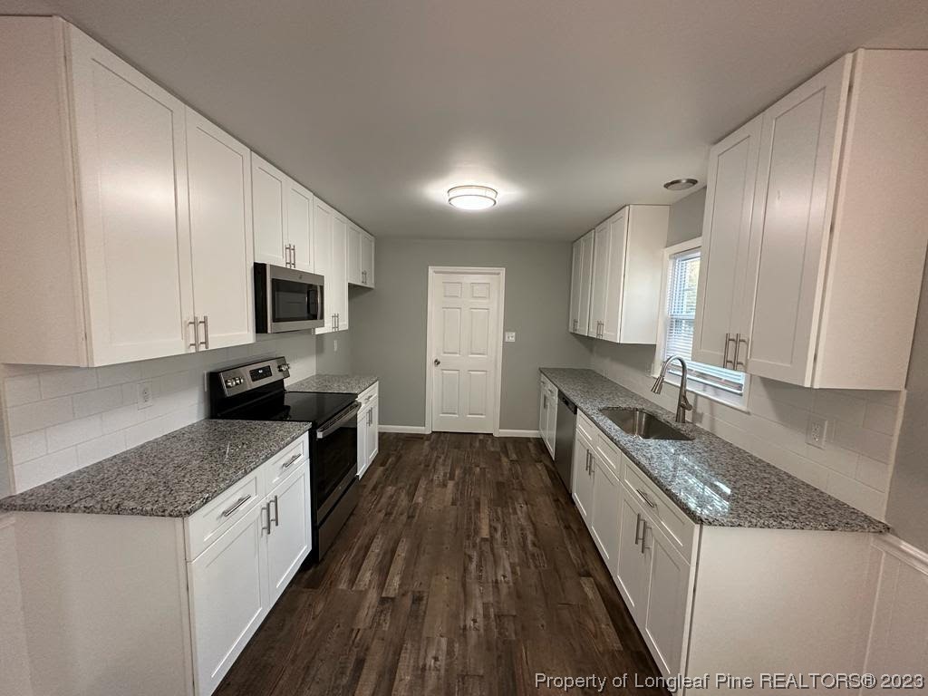 4553 Ruby Road Fayetteville, NC 28311 - Photo 5 of 19 a large kitchen with a stove sink microwave and cabinets