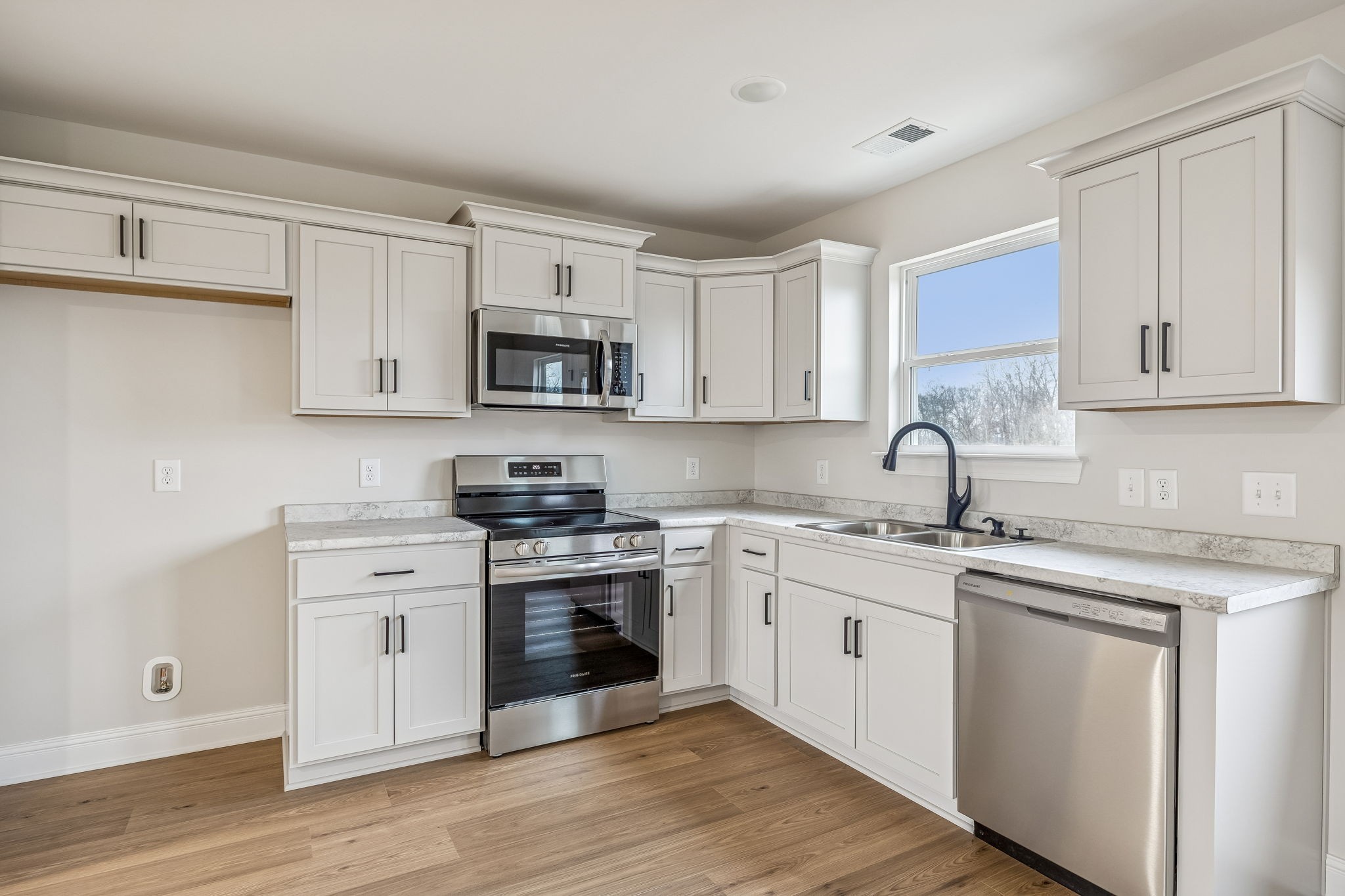 1057 Landing Lane Adams, TN 37010 - Photo 9 of 29 a kitchen with stainless steel appliances granite countertop white cabinets a sink a stove a refrigerator and microwave with wooden floor