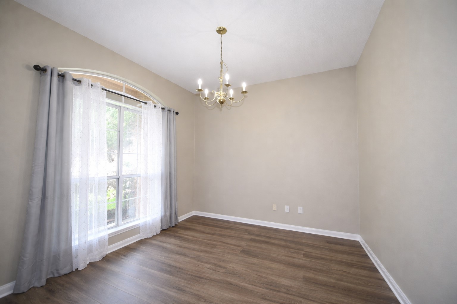 9611 Babbling Spring Court Tomball, TX 77375 - Photo 5 of 31 Bright dining room with large window, elegant chandelier, neutral walls, and wood flooring. Perfect for cozy meals and entertaining.