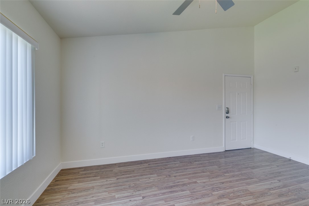 6650 West Warm Springs Road, Unit 2118 Las Vegas, NV 89118 - Photo 27 of 41 A well-lit room featuring durable wood flooring and ample vertical blinds for privacy.