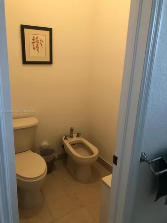 a white toilet sitting next to a white sink and vanity