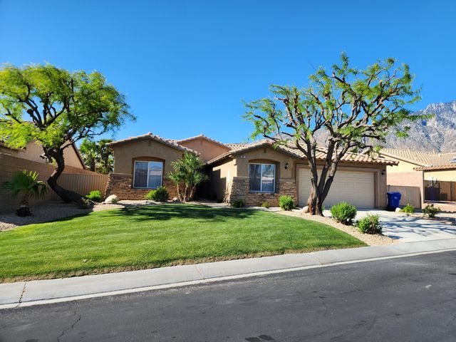 a front view of a house with a garden and tree