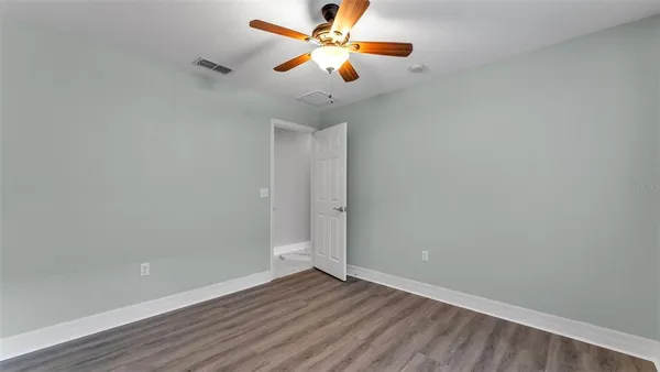 an empty room with window and chandelier fan