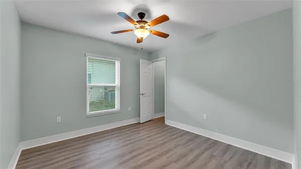 an empty room with wooden floor and a ceiling fan