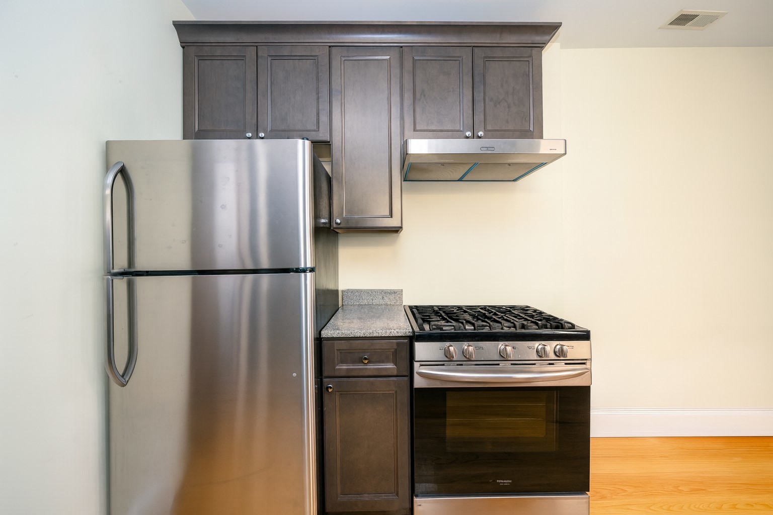 5501 West School Street, Unit 1C Chicago, IL 60641 - Photo 4 of 11 a kitchen with granite countertop a refrigerator stove and cabinets