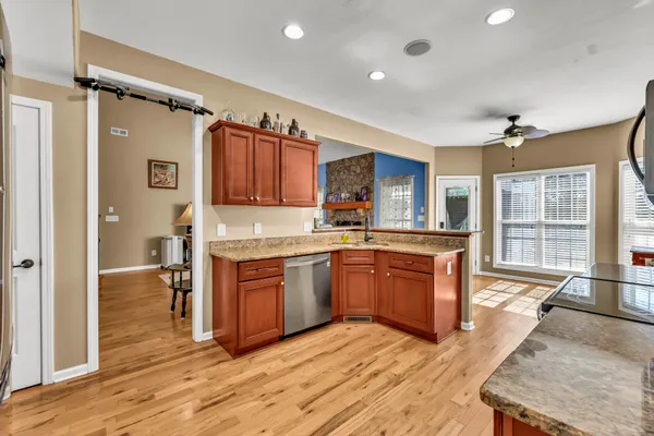 a large kitchen with stainless steel appliances granite countertop a refrigerator a sink dishwasher a stove with wooden cabinets and floor