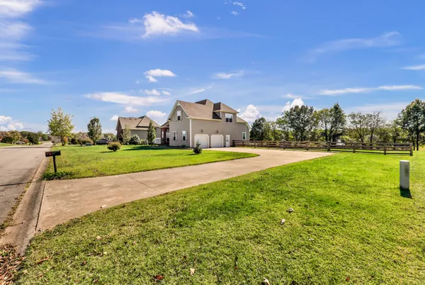 a view of a big house with a big yard and large trees