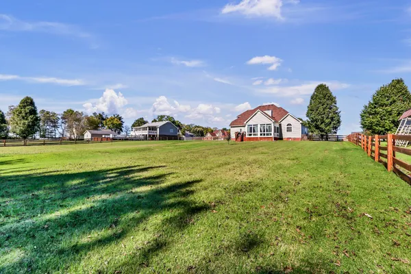 a view of a house with a big yard and large trees