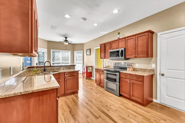 a large kitchen with stainless steel appliances granite countertop a sink stove and refrigerator