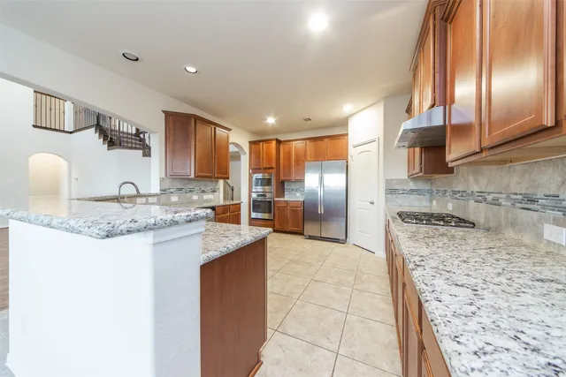 a kitchen with stainless steel appliances granite countertop a sink stove and refrigerator